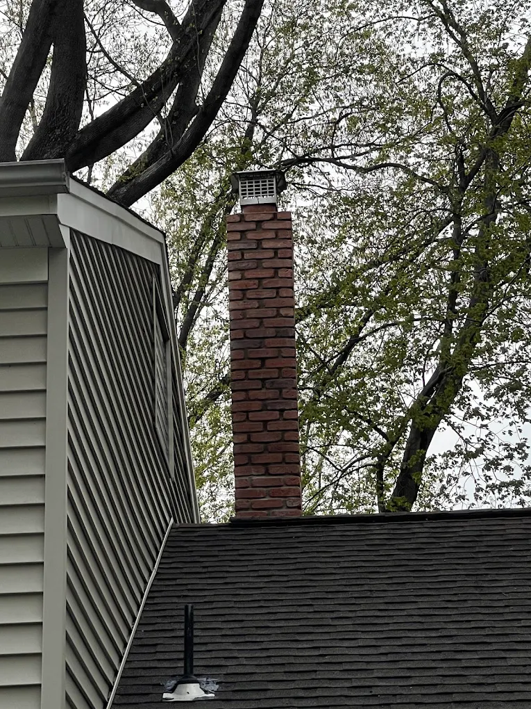 Finished brick chimney against a dark architectural roof